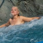 Blonde Naked Woman Enjoying Her Vacation in Hot Tub Bubbling Water in Summer Sun Stock Photo